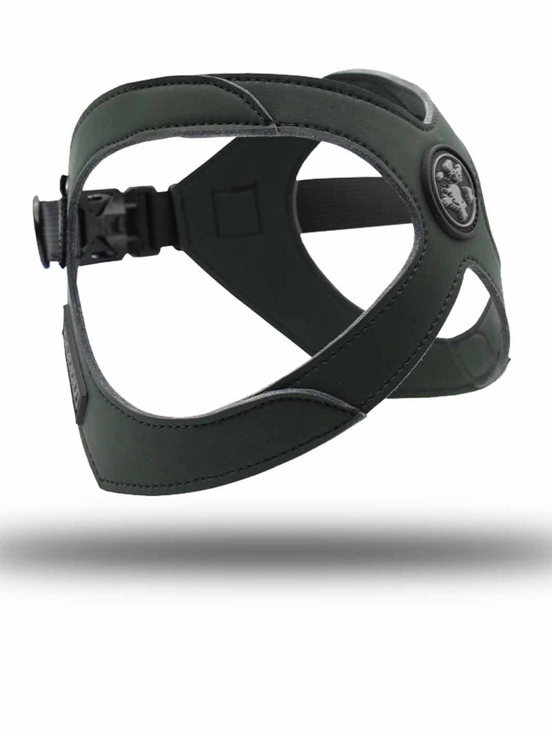 A dark moss green french bulldog harness floats above the floor against a white background.