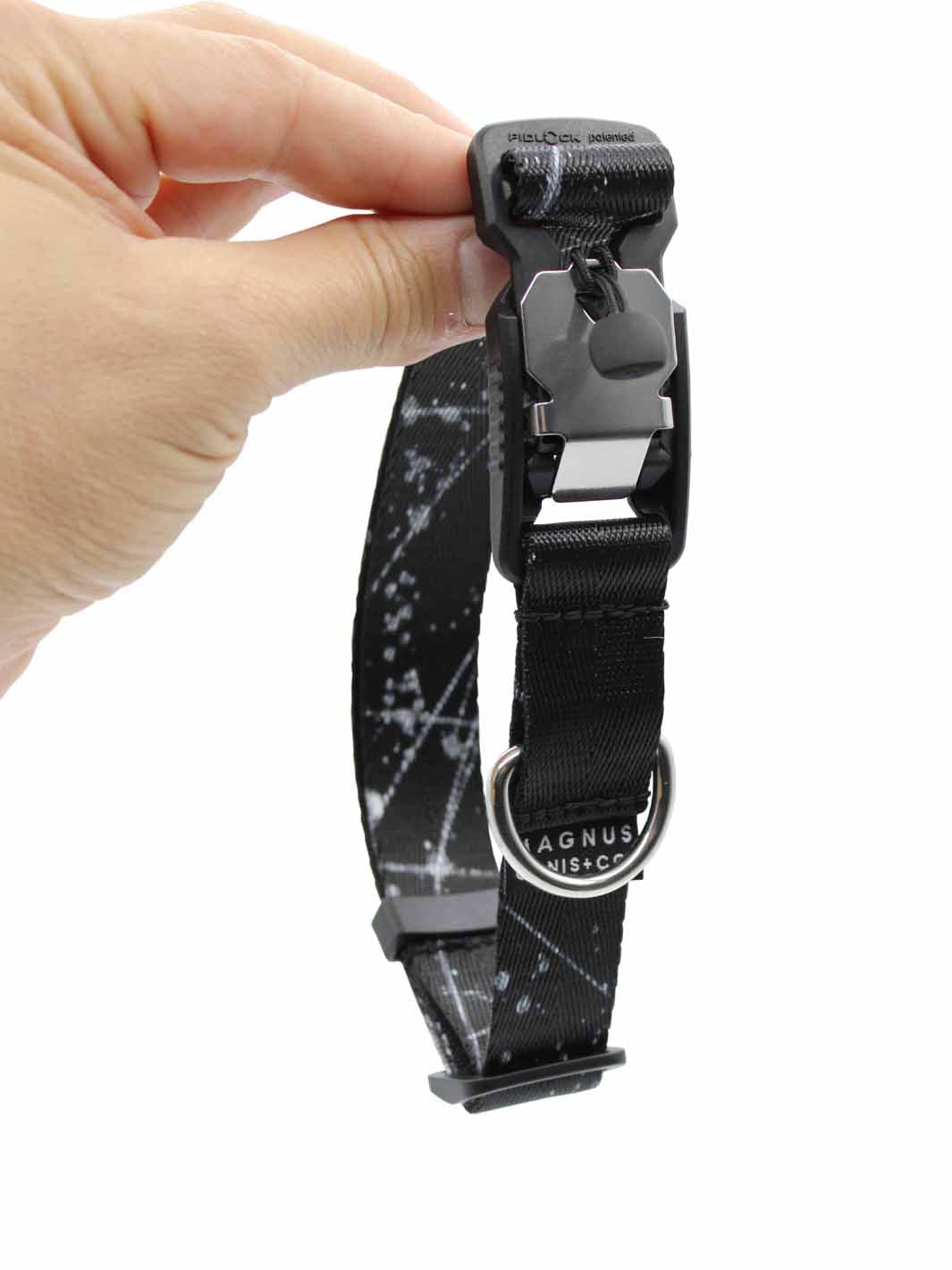 A black nylon strap dog collar with white spatter print design and a magnetic buckle being held vertically.
