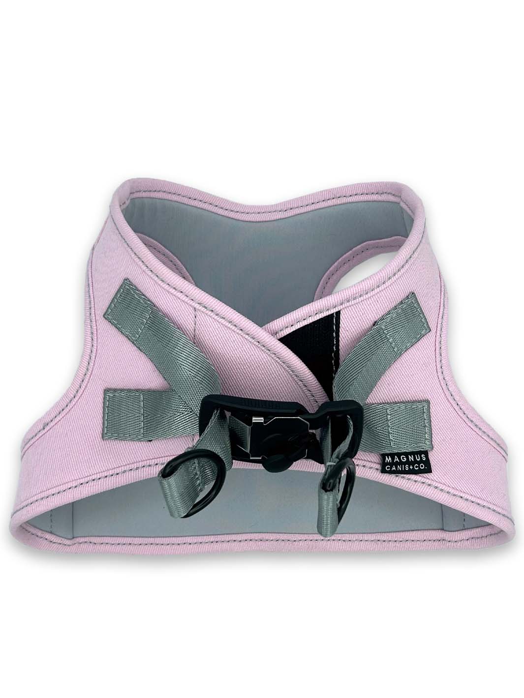 A pale pink made in america denim dog harness laying on a white surface.