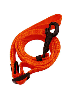 Neon orange dog leash with black trims in nylon strap coiled on surface.